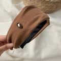 Dettaglio di un cerchietto di peluche marrone con decorazione a cane dorato e texture - Marrone