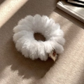 Close-up of a white fluffy hair scrunchie with a cute deer tag on textured fabric - White
