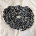 Close-up of black and white crochet knit scrunchie with hollow pattern and woven label - Dark Gray