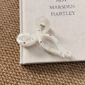 Close-up of cream resin bow hair claw clip with colorful rhinestones on a book - Bowtie Claw Clip