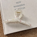 Detail of cream white marble hair claw clip with colorful rhinestones on book cover - Cross Claw Clip