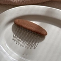 Detail eines braunen Haarkamms aus Filz mit zehn silbernen Metallzähnen auf Tablett - Braun