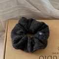 Détail d'un chouchou en polaire gris foncé avec une étiquette logo nœud blanc - Noir