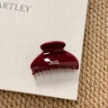 Close-up of wine red resin hair claw clip with gold lettering and fine glitter finish - Semi-circle Style