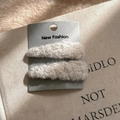 Close-up of two light beige sherpa fleece teardrop hair clips on a card display - Off White