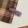 Primer plano de un clip de pelo de felpa morada sobre tela a cuadros marrón para invierno - Triángulo / Morado