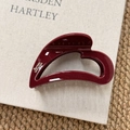 Detailed view of dark red acrylic hair claw clip with golden glitter and brand logo label - Heart Style