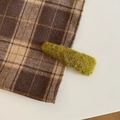 Primer plano de pinza de pelo de felpa verde musgo suave sobre tela de cuadros marrón - Triángulo / Amarillo y Verde