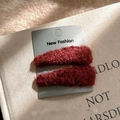 Paire de barrettes à cheveux pelucheuses rouge foncé sur une carte avec fond livre ancien - Rouge