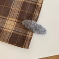 Detail shot of a grey plush oval hair clip textured with soft faux fur on plaid fabric - Oval / Gray