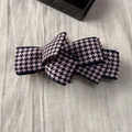 Détail de la pince à cheveux avec nœud en tissu à motif pied-de-poule rose et noir - Style à Carreaux Rose