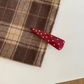 Close-up of a vintage red hair clip with white polka dots on a plaid background fabric - Long Triangle Style