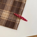 Close-up of red and white polka dot hair clip on a textured fabric background - Pointed Leaf Style