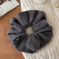 Détail du chouchou en maille gris foncé avec petite étiquette nœud sur tissu doux - Gris foncé
