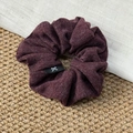 Détail de la texture d'un chouchou tricoté bordeaux avec petite étiquette à nœud noir - Rouge Vin Foncé