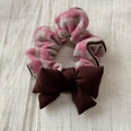 Détail d'un chouchou à carreaux rose et gris avec un nœud brun sur fond de lin - Scrunchie Nœud