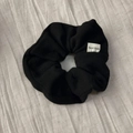 Close-up of black fabric scrunchie with knit texture and white Hand Made woven label - Black