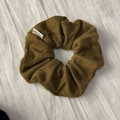 Detailed close-up of an olive brown knitted scrunchie with handmade fabric label - Turmeric