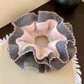 Detail van de gebreide scrunchie in grijs en roze met golfsteken op beige textuur - Oudroze