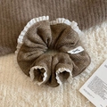 Dettaglio macro dello scrunchie in maglia marrone con bordi in pizzo e logo tessuto - Cachi