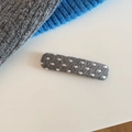 Detailansicht einer grauen Strick-Haarklammer mit weißem Punktmuster auf beigem Grund - Rechteckige Form (5995598465860) / Graues Rechteck