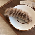 Dettaglio del fermaglio a banana in peluche leopardato con morbida pelliccia su piatto bianco - Marrone
