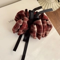 Detailopname van rode geruite scrunchie met zwart lint op witte rekwisieten en houten tafel - Rood Geruit Lint
