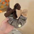 Detail of knitted bow scrunchie with stripes and decorative button in a warm setting - Striped Scrunchie