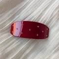 Dettaglio ravvicinato di una clip per capelli bordeaux con strass su tessuto bianco - Stile cielo stellato / Rosso