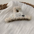Detail of plush knit hair claw clip with woven tag and silver smile button - Hair Claw / Off White