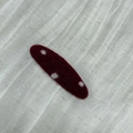 Detailed close-up of dark burgundy wool felt hair clip with three white polka dots - Red Oval