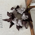 Detailed view of large taupe scrunchie with dark brown ribbons on a wooden box - Coffee