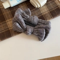 Detailaufnahme einer grauen gestrickten Haarklammer mit weicher Winterschleife und feinen Nähten - Grau