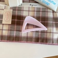 Detail of elegant cherry pink hollow geometric shark hair claw clip on fabric background - Triangle