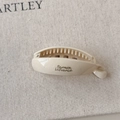 Close-up of ivory resin banana hair clip with gold lettering and comb teeth detail - Small Creamy White
