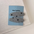 Detail of two gray felt hair clips with black polka dots on blue display card - Gray Polka Dot Oval