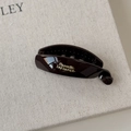 Macro detail of dark brown resin banana hair clip with elegant golden French lettering - Small Brown
