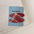 Detailed close-up of red plaid fabric hair clips on a New Fashion display card - Red Plaid Oval