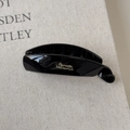 Close-up of black resin banana hair clip with gold Barrette La France text on linen - L Black