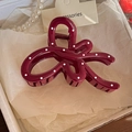 Dettaglio di una molletta per capelli bordeaux a pois in una confezione regalo - Pinza a Farfalla