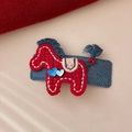 Detailed close-up of a handmade red knitted pony hair clip with blue denim base texture - Red Pony Denim Style