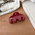 Detailed view of large dark red resin shark hair claw clip on wooden desk setting - Red Curved