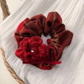 Gros plan d'un chouchou à carreaux rouge avec fleur au crochet et détail de nœud en velours - Chouchou Fleur