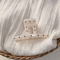 Detail of cream hair claw clip with black polka dots on soft fabric in a woven basket - White Straight Style