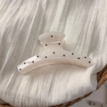 Detailed view of large cream hair claw clip with black polka dots on white fabric - White Hanger Style