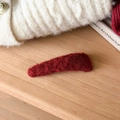 Detailed close-up of dark red plush hair clip on a cozy wooden and knit background - Fine Triangle