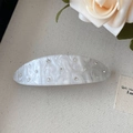 Close-up of moonlight white acetate hair clip with 13 rhinestones on burlap fabric - White Spring Clip