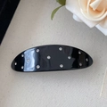 Detail showing shiny black acetate hair clip with sparkling rhinestones on white fabric - Black Spring Clip