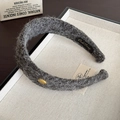 Detalle de una diadema de felpa gris con logo de metal dorado y textura suave aterciopelada - Gris