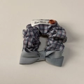 Dettaglio dello scrunchie a quadri blu-grigio con bottone in legno e etichetta - Elastico Plaid Blu Grigio con Fiocco